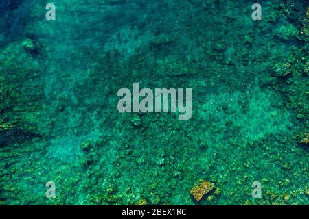 Aerial of ridge of jagged rock on ocean floor. Mediterranean reef, coral, or sand just above or below the surface of the sea Stock Photo
