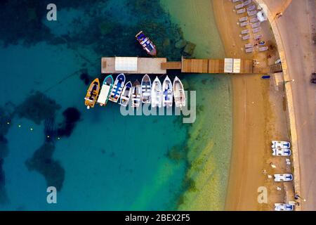 A small peer with boats on a beach aerial. Beautiful torquoise waters of mediterranean sea. Boat parked near island Stock Photo