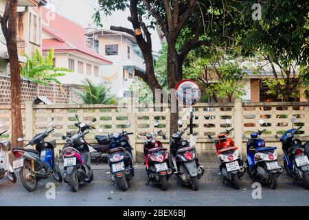 Chianf Mai, Thailand - February 9, 2020: rows of parked motorbikes on parking on street of Chiang Mai in Northern Thailand Stock Photo