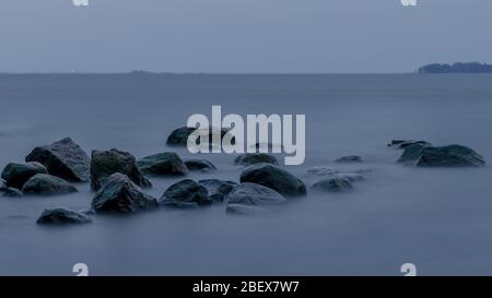 Rocks in silky seawater in winter storm Stock Photo