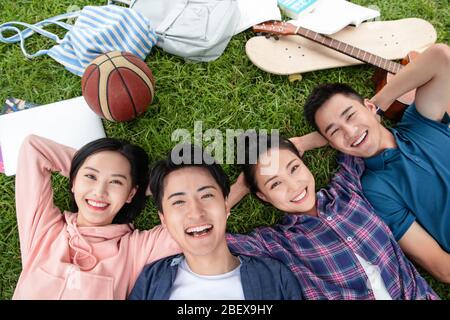 Happy students lay on the grass Stock Photo
