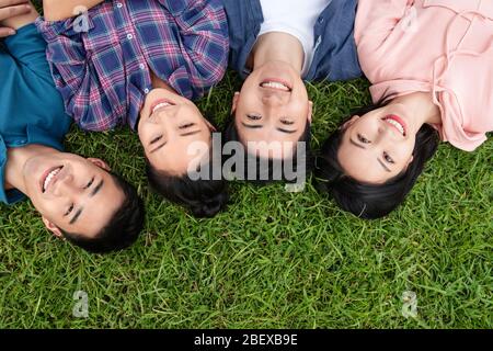 Happy students lay on the grass Stock Photo