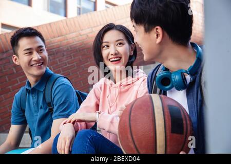 Happy students sit chatting on the stairs Stock Photo