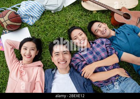 Happy students lay on the grass Stock Photo