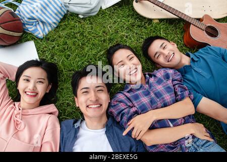 Happy students lay on the grass Stock Photo