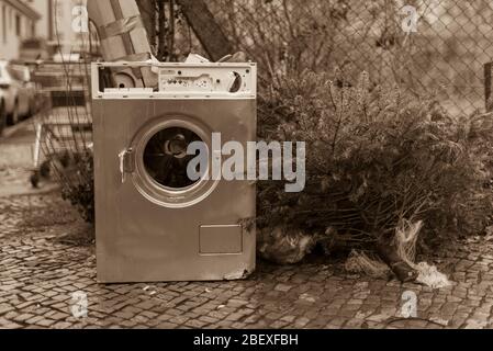 Old washing machine standing on the sidewalk, junk on the street, household waste, bulky waste on the street, black and white photo Stock Photo