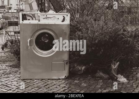 Old washing machine standing on the sidewalk, junk on the street, household waste, bulky waste on the street, black and white photo Stock Photo