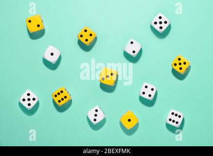 Top view of randomly scattered yellow and white dice on a green background with shadows in an indoor games and gambling concept viewed from above Stock Photo