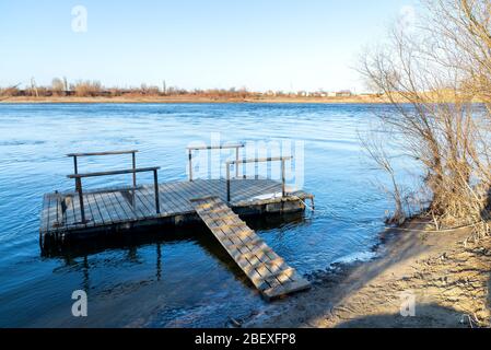 Spacious pedestrian pier made of wood on pontoons, easy boarding in boats or fishing. Stock Photo