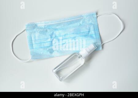 Sanitizer with a mask on a white table - concept of protection against coronavirus COVID-19. Close up. Stock Photo