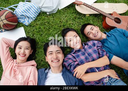 Happy students lay on the grass Stock Photo