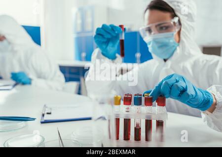 biochemist holding test tube with blood sample near colleague in laboratory Stock Photo