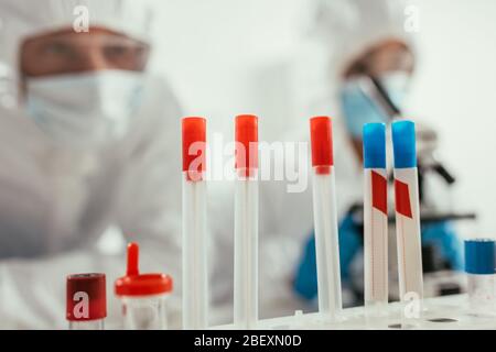 selective focus of test tubes near biochemists in laboratory Stock Photo