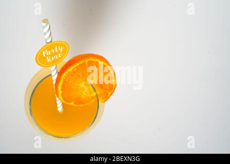 An orange cocktail fruit drink in a glass with a party straw looking down on a plain white background Stock Photo