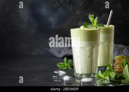 Two glasses of Dalgona iced latte matcha tea and ingredients on black background. Copy space. Close up. Stock Photo