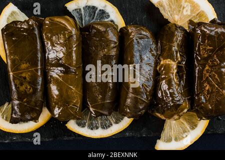 Dolma (stuffed grape leaves) top view on a black background. Mediterranean cuisine vegan dish Stock Photo