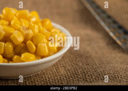 Corn seeds in a white saucer on the table Stock Photo