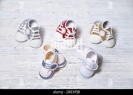 multi-colored children's shoes on a white-gray non-uniform wooden background close-up Stock Photo