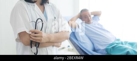 Healthcare and medical concept, close up doctor holding stethoscope with old patient laying down on bed Stock Photo