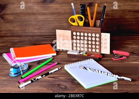Colorful notebooks of pencils calendar and a stapler on a brown wooden background. Inscription in notepad it,s love Stock Photo