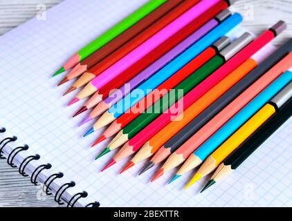 Color pencils lying on a pad with a spiral. Gray natural background, blur Stock Photo