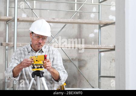 construction man worker measure with level laser wear hard hat and protective glasses  at interior building site Stock Photo