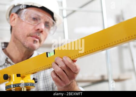 construction man worker measure with level laser wear hard hat and protective glasses  at interior building site Stock Photo