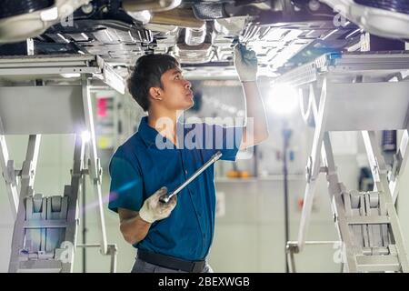 Closeup Asian mechanic hand repairing under the car in maintainance  service center which is a part of showroom, technician or engineer professional w Stock Photo