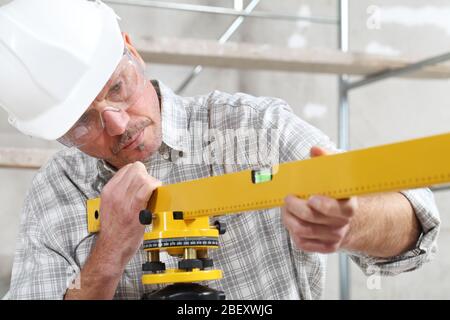 construction man worker measure with level laser wear hard hat and protective glasses  at interior building site Stock Photo