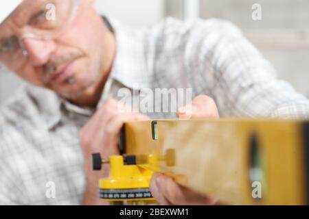 construction man worker measure with level laser wear hard hat and protective glasses  at interior building site Stock Photo