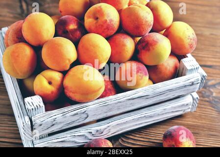 apricots in a white wooden box on a natural wooden brown background, close-up Stock Photo