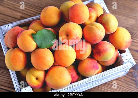 Fresh juicy, natural apricots in a white wooden box on a natural wooden brown background, close-up copy space Stock Photo