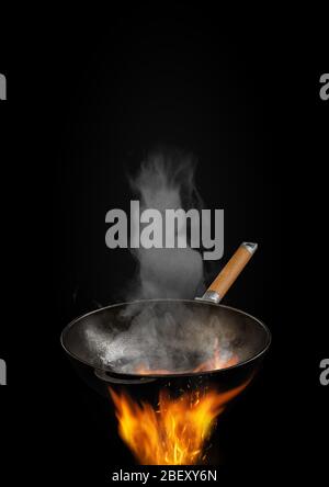 Empty wok pan with smoke above fire with sparks against black ...