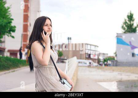 Girl speak by telephone on waterfront. Girl in the city on a summer day Stock Photo