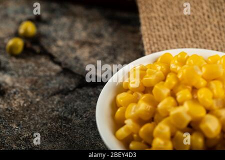 Marinated corn seeds in a white saucer on a piece of burlap Stock Photo
