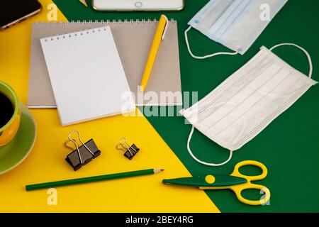 Working at home. Medical mask on the desktop. Remote work and study. Telework, freelance. Notepad with place for text and pen for notes. Layout Stock Photo