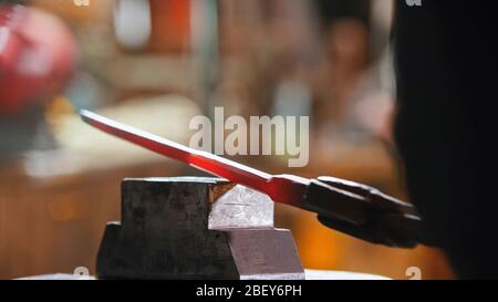 Making a knife out of hot metal using a pressure machine. Mid shot Stock Photo