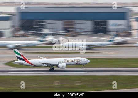 Lantau, Hong Kong  - April 10, 2020 :   Emirates SkyCargo airplane is landing in runway, passenger airplanes are parking at maintenance area because o Stock Photo