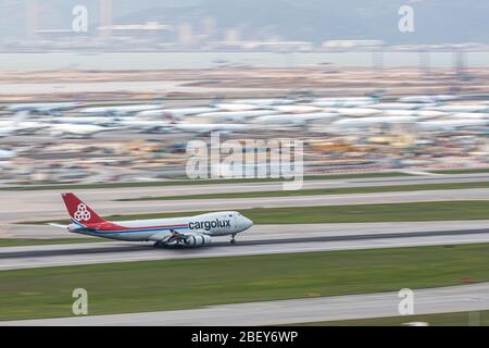 Lantau, Hong Kong  - April 10, 2020 :  Cargolux airplane is landing in runway, passenger airplanes are parking at maintenance area because of COVID-19 Stock Photo