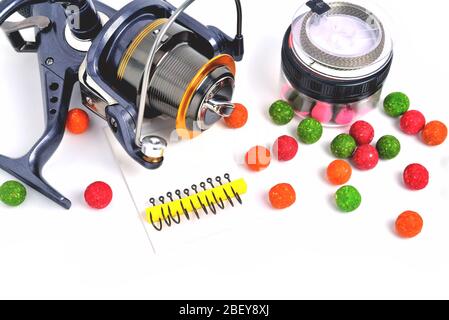 Fishing coil, carp hooks colored boilies, braided cord, on white background, close-up Stock Photo