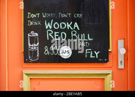 Chalkboard advertising on an orange door of a pub in Düsseldorf Old Town, which is a popular tourist area with many restaurants and bars. Stock Photo