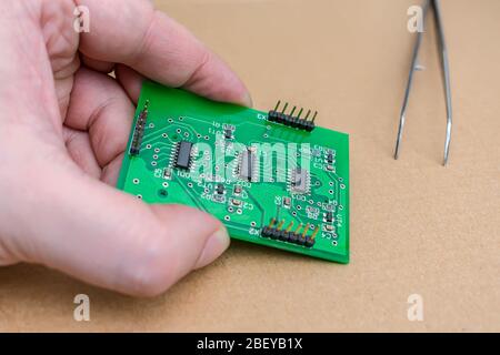 Electronic microcircuit in the hands of the master on the repair table Stock Photo