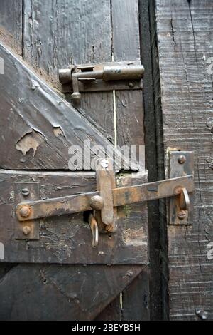 gate latch, showing rust and evidence of being painted several times,  on a british residential garden gate, with bolt lock above Stock Photo