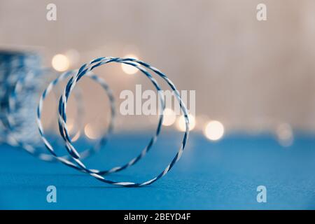 Blue and white rope for gift packages in the form of a spiral on a blue background with a bright glow in the background. Selective focus. Stock Photo