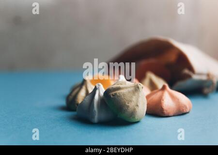 Colorful meringues and a small cloth bag decorated with white snowflakes on a blue background. Selective focus. Stock Photo