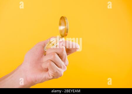 Hand holding antique brass compass isolated on yellow background with copy space for text Stock Photo