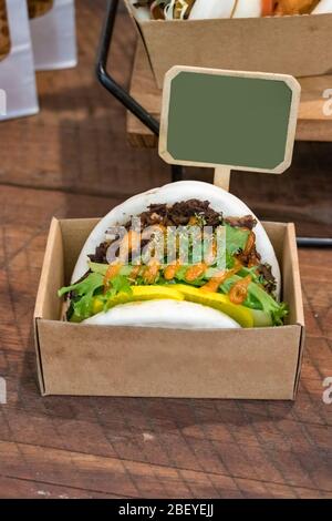 A Bulgogi asian beef burger bun placed on a cardboard box for sale a a restaurant counter Stock Photo
