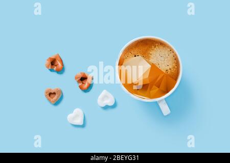 Morning cup of strong coffee with five pieces of sugar in the shape of hearts on blue background. Stock Photo