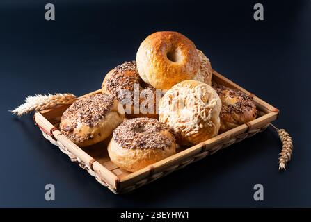 Food bakery concept Homemade organic bagels in bamboo wicker tray on black background Stock Photo