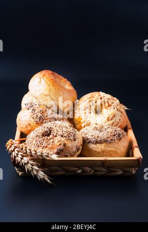 Food bakery concept Homemade organic bagels in bamboo wicker tray on black background Stock Photo